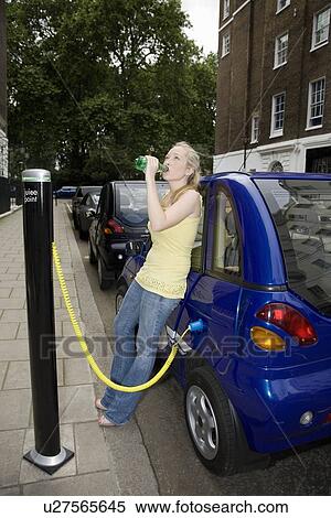 Young woman drinking by electric car View Large Photo Image Stock Photography - Young woman drinking by electric car. Fotosearch