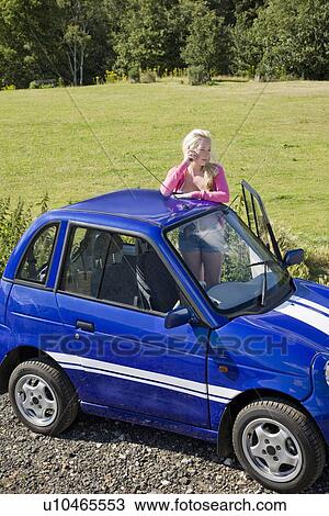 Young woman on phone by electric car View Large Photo Image Stock Image - Young woman on phone by electric car. Fotosearch