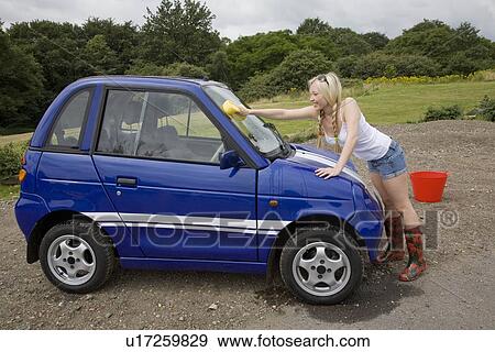Stock Photo - Young woman washing electric car. Fotosearch