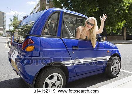 Young woman waving from electric car View Large Photo Image Stock Photo - Young woman waving from electric car. Fotosearch