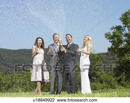 Stock Image - Wedding party popping champagne. Fotosearch