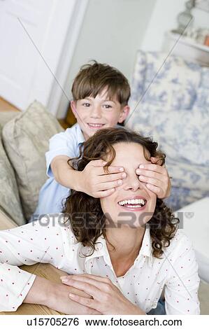 Boy holding the eyes of his mum closed View Large Photo Image Stock Photograph - Boy holding the eyes of his mum closed. Fotosearch