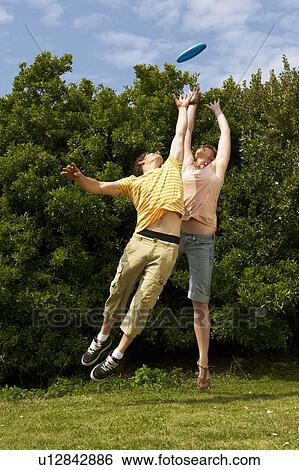 Stock Photograph - Couple jumping to catch a frisbee. Fotosearch