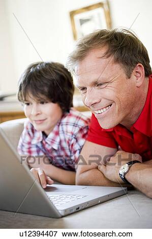 Stock Photo - Father and son smiling into laptop. Fotosearch