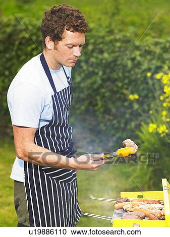 Man inspecting lamb chop at barbecue View Large Photo Image Stock Image - Man inspecting lamb chop at barbecue. Fotosearch