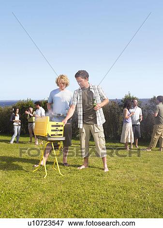 Man tending barbecue with friend View Large Photo Image Stock Photo - Man tending barbecue with friend. Fotosearch