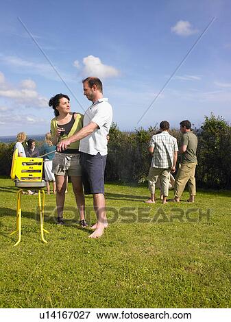 Man tending barbecue with woman View Large Photo Image Stock Photo - Man tending barbecue with woman. Fotosearch