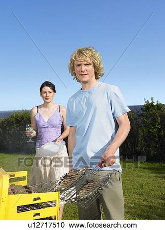 Stock Image - Man with two barbecued fish. Fotosearch