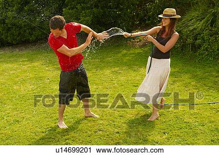 Woman spraying man with garden hose View Large Photo Image Stock Image - Woman spraying man with garden hose. Fotosearch