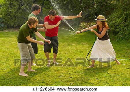 Woman spraying men with garden hose View Large Photo Image Picture - Woman spraying men with garden hose. Fotosearch