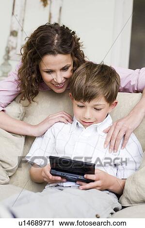 Woman watching her son video playing View Large Photo Image Stock Image - Woman watching her son video playing. Fotosearch