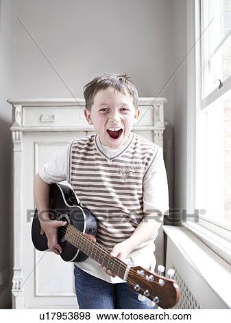 Young boy standing playing guitar View Large Photo Image Stock Photo - Young boy standing playing guitar. Fotosearch