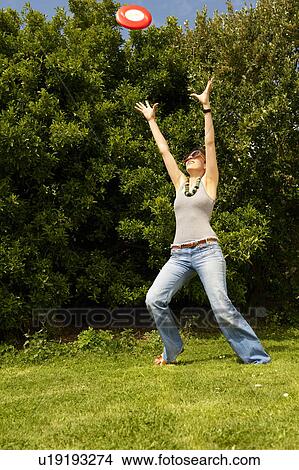 Picture - Young woman trying to catch a frisbee. Fotosearch