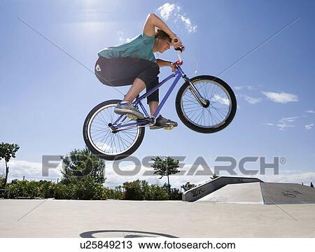 Stock Image - Teen boy on bike jumping. Fotosearch
