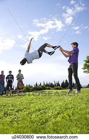 Teen boys help friend to do a flip View Large Photo Image Stock Image - Teen boys help friend to do a flip. Fotosearch