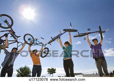 Teen boys lifting bikes in air View Large Photo Image Stock Photo - Teen boys lifting bikes in air. Fotosearch