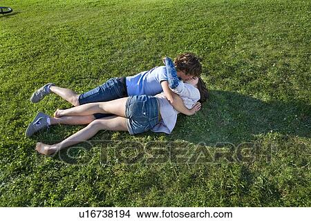 Teen couple laying on grass, kissing View Large Photo Image Picture - Teen couple laying on grass, kissing. Fotosearch