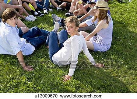 Stock Image - Teen group sitting on grass. Fotosearch