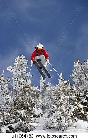 Skier jumping over snow covered trees View Large Photo Image Stock Image - Skier jumping over snow covered trees. Fotosearch