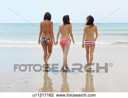 Stock Image - Three girls walking towards the sea. Fotosearch