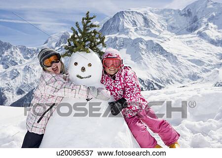 Two girls with a snowman View Large Photo Image Stock Photo - Two girls with a snowman. Fotosearch
