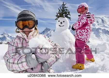 Stock Photograph - Two girls with a snowman. Fotosearch