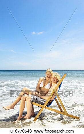 Young couple sharing a deck chair View Large Photo Image Stock Image - Young couple sharing a deck chair. Fotosearch