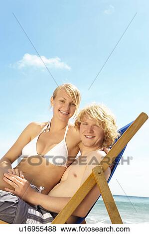 Young couple sharing a deck chair View Large Photo Image Stock Photo - Young couple sharing a deck chair. Fotosearch