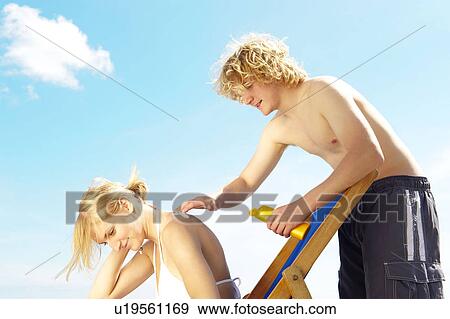 Young man applying sun cream on woman View Large Photo Image Stock Photo - Young man applying sun cream on woman. Fotosearch