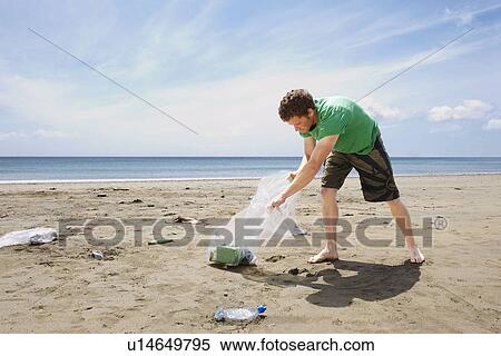 Young man collecting garbage on beach View Large Photo Image Stock Photography - Young man collecting garbage on beach. Fotosearch