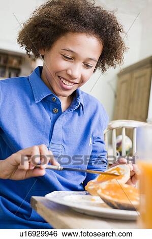 Stock Photograph - Boy putting marmalade on his bread. Fotosearch