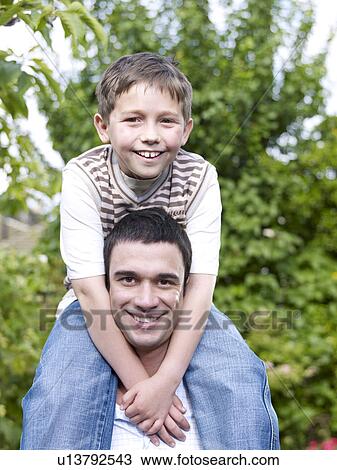 Boy sitting on mans shoulders View Large Photo Image Stock Image - Boy sitting on mans shoulders. Fotosearch