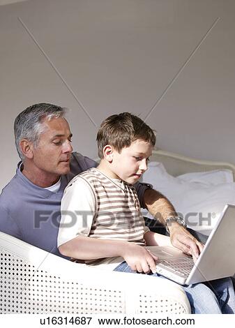 Father and son on laptop in bedroom View Large Photo Image Stock Photo - Father and son on laptop in bedroom. Fotosearch