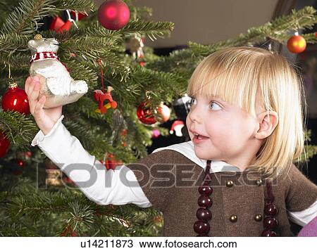 Stock Image - Girl playing with christmas decoration. Fotosearch