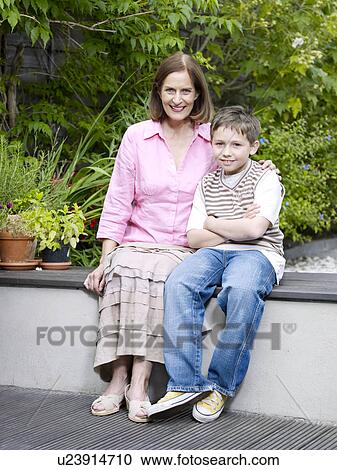 Stock Image - Mum and son sitting on patio in garden. Fotosearch