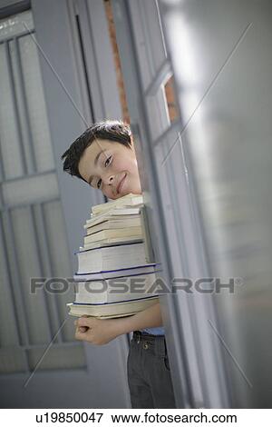 Stock Photo - School boy holding stack of books. Fotosearch