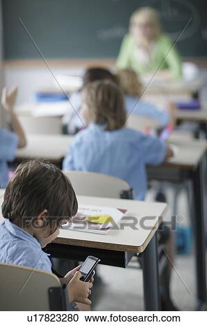 School boy texting in class View Large Photo Image Stock Image - School boy texting in class. Fotosearch