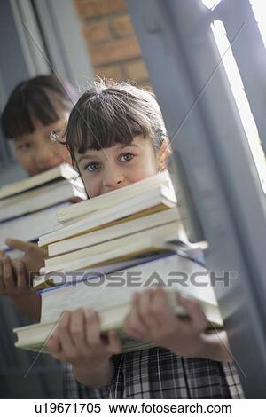Stock Photography - School girls holding stacks of books. Fotosearch
