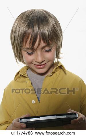 Young boy playing with handheld game View Large Photo Image Stock Image - Young boy playing with handheld game. Fotosearch