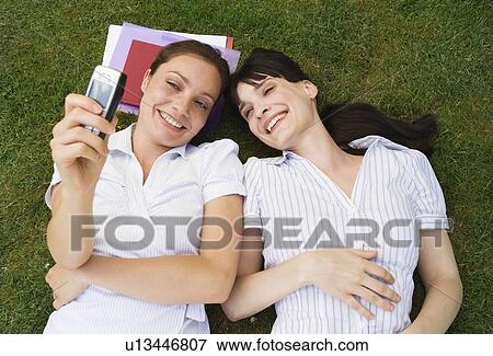 Stock Photo - 2 women taking photo with mobile. Fotosearch