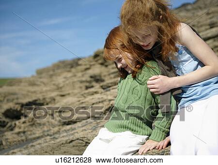 Girl hugging young sister on rocks View Large Photo Image Stock Photo - Girl hugging young sister on rocks. Fotosearch