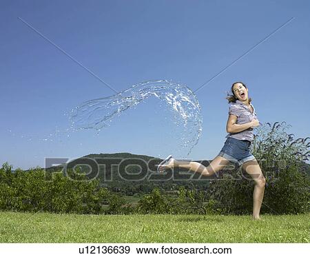 Girl running from arc of water View Large Photo Image Stock Photo - Girl running from arc of water. Fotosearch