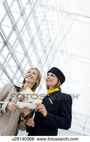 Stock Photo - Stewardess showing woman directions. Fotosearch