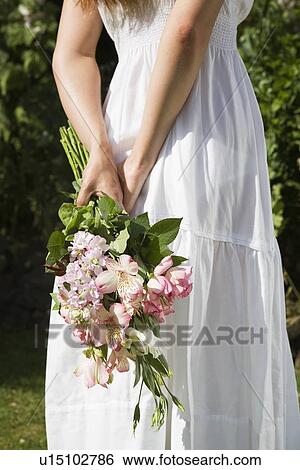 Woman holding bouquet behind back View Large Photo Image Stock Photograph - Woman holding bouquet behind back. Fotosearch
