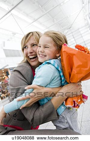 Woman holding flowers embracing girl View Large Photo Image Stock Photo - Woman holding flowers embracing girl. Fotosearch