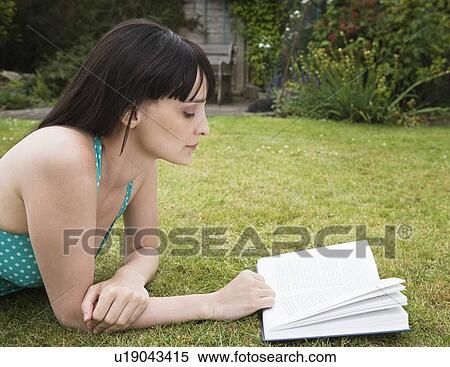 Stock Photography - Woman reading book in garden. Fotosearch