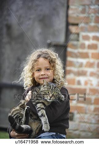 Stock Photo - Young girl holding pet cat outside. Fotosearch