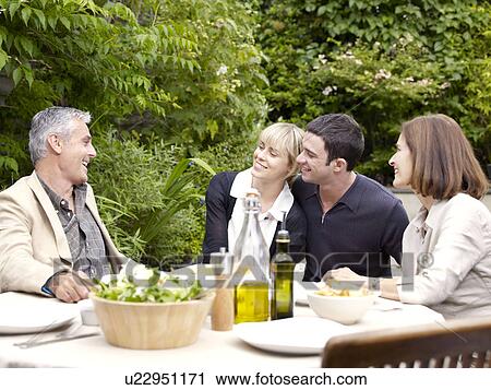 Stock Image - Family sitting having lunch in garden. Fotosearch