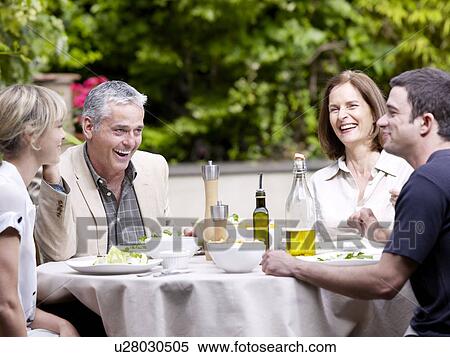 Stock Photography - Family sitting having lunch in garden. Fotosearch