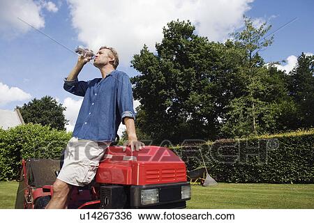 Man drinking water by lawn mover View Large Photo Image Stock Photograph - Man drinking water by lawn mover. Fotosearch